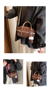 Detail view of brown suede mini crossbody bag with fuzzy ball charm and adjustable strap