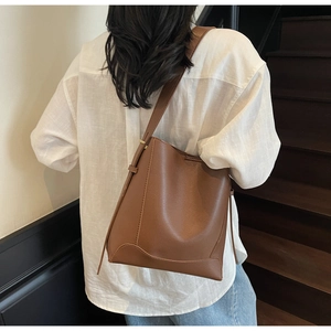 Deep brown bucket bag featuring wide adjustable strap and pebbled leather texture
