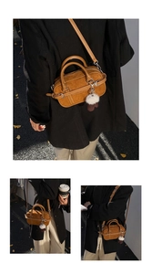 Detail of brown textured leather shoulder bag with white fur ball charm and shoulder strap