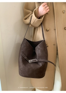 Détail du sac seau marron foncé avec surpiqûres blanches et boucle argentée