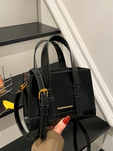 Chic black glossy square handbag with double handles and a slender adjustable shoulder strap