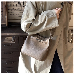Close-up of litchi grain leather bucket bag with metal buckle and shoulder strap detail