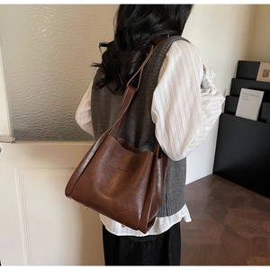 Detail of dark brown vintage faux leather tote with metallic rivets and embossed logo