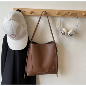 Detailed view of dark brown pebbled leather texture and stitching on a large tote bag