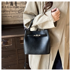 Detail of black lychee grain leather bucket bag with silver buckle on khaki trench coat