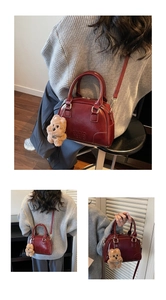 Detail of dark red Boston bag with MKXQ logo and plush dog charm in life scene