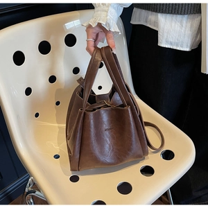 Detail view of the brown vintage bucket bag with adjustable strap and metal hardware