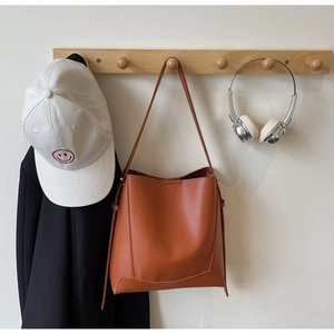 Detail of caramel faux leather bucket bag showing soft lychee grain texture and drawstring