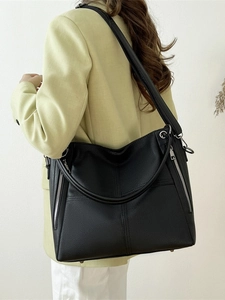 Large black crescent tote bag with pebble texture and dual straps on casual outfit