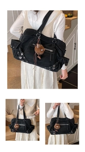 Detail of a black oversized tote bag with silver zippers and a brown plush keychain
