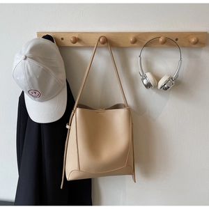 Detail view of large apricot leather bucket bag with drawstring on wooden rack