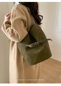 Détail d'un sac seau vert olive en daim avec boucle métallique porté par un mannequin