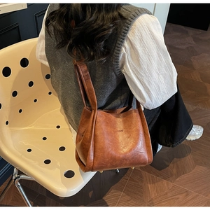 Caramel brown leather bucket bag detail showing metal feet and embossed logo on the bottom