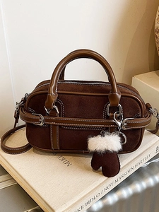 Sac bowling vintage en daim marron foncé avec coutures blanches et pendentif