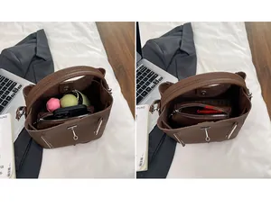 Detail view of brown leather bucket bag interior with laptop and work accessories