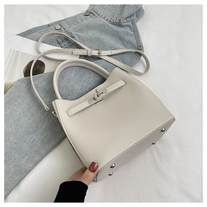 Detail of off-white lychee grain leather handbag with silver metal feet and strap closure