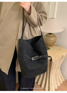 Détail d'un sac seau noir mat avec surpiqûres contrastées et boucle décorative chic