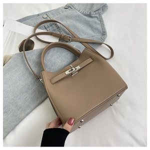 Close-up of brown pebbled leather handbag with metallic turn-lock and handle detail