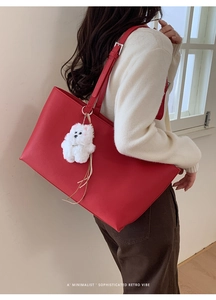 Detail of red leather tote bag with white plush dog charm for sophisticated retro style