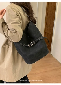 Détail du sac seau en daim noir avec surpiqûres blanches et fermeture à boucle minimaliste