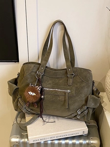 Olive green vintage tote bag with rivets and plush charm on a silver suitcase