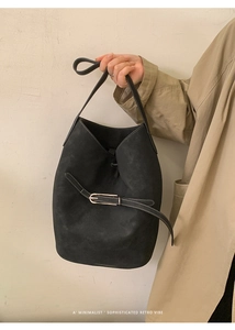 Détail d'un sac seau vintage en daim noir avec fine ceinture et boucle en métal argenté
