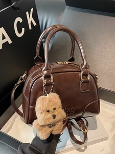 Dark brown patent leather Boston bag with plush puppy charm for women’s daily commute