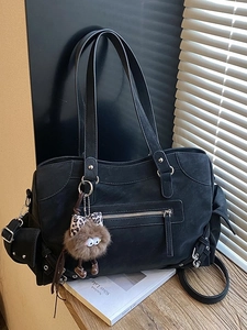 Retro black large tote bag with monster charm on wooden table in soft lighting