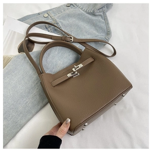 Detailed close-up of dark brown pebble leather handbag with classic metal buckle and handle