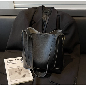 Detail of black pebbled leather bucket bag with gray edges and gold-tone hardware