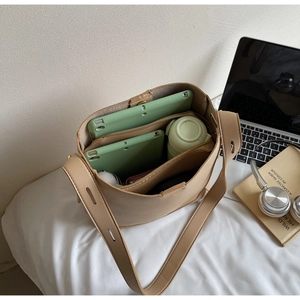 Top-down view of spacious beige bucket bag interior with laptop and travel essentials