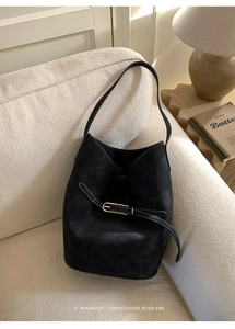 Détails d'un sac seau noir en daim avec surpiqûres contrastées et boucle élégante
