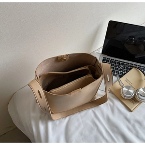 Detail of beige bucket bag with large interior space and a zippered inner pouch