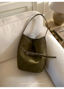 Détail du sac seau vert olive vintage avec boucle argentée sur canapé blanc