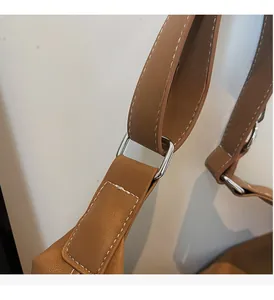 Dettaglio macro delle fibbie argentate e cuciture a contrasto su borsa tote in pelle