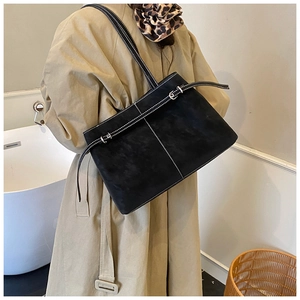 Close-up of black suede tote bag with white contrast stitching and buckle detail