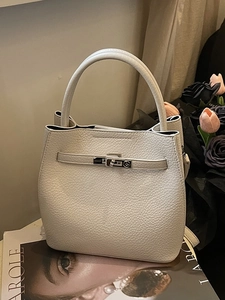 Chic beige lychee grain leather bucket bag with silver twist lock on fashion magazine