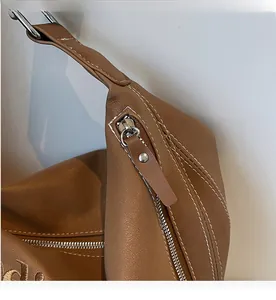 Dettaglio della cerniera in metallo e cuciture a contrasto su borsa tote in pelle marrone