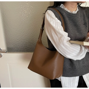 Detail of soft brown pebble leather shoulder bag showing the texture and wide strap