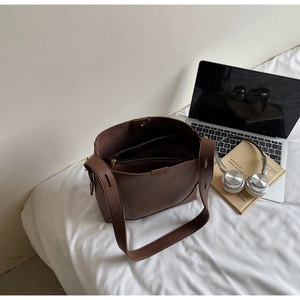 Detail of dark brown leather bucket bag with inner zipper pouch and magnetic closure
