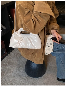 Chic beige pleated cloud tote bag styled with a brown coat and casual denim look