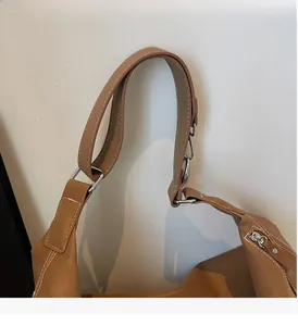 Dettaglio tracolla in pelle marrone con cuciture bianche a contrasto e anello metallico