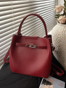 Minimalist red leather bucket handbag with gold buckle and adjustable strap