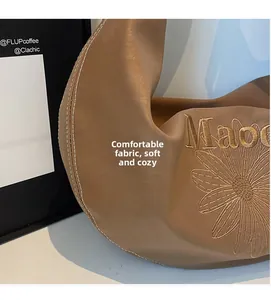 Dettaglio ravvicinato della borsa tote in pelle color cammello con ricamo a margherita