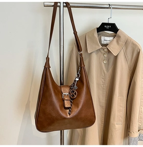 Detail of a dark brown vintage hobo bag with a silver buckle and woven strap ornament