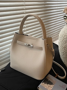 Cream lychee textured leather tote bag with silver buckle in natural window light