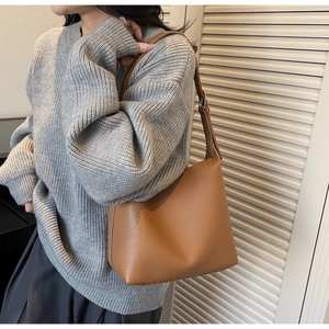 Close-up of brown litchi pattern leather shoulder bag with silver hardware on a model
