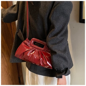 Detail of burgundy pleated patent leather tote bag with glossy finish and matching shoulder strap