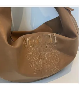 Dettaglio del ricamo Maodi e del motivo a margherita sulla borsa tote marrone