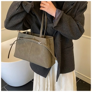 Detail of green tote bag with white contrast stitching and silver buckle on shoulder strap